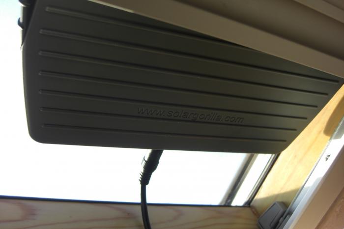 Laptop power adapter tucked under a shelf by a window