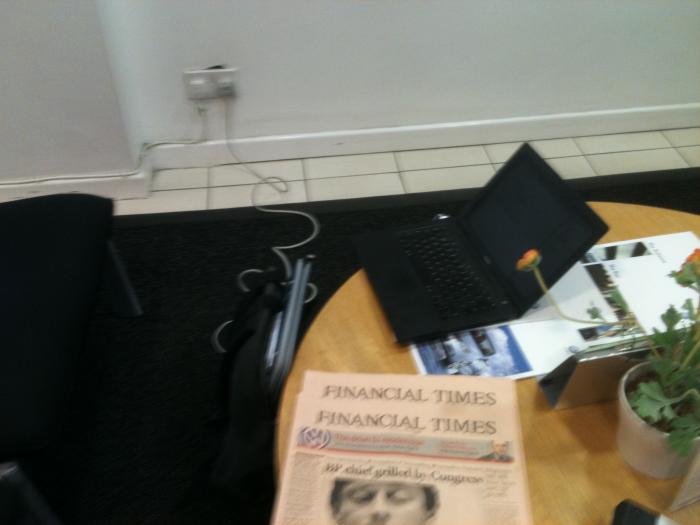 Laptop, coffee and newspaper on a table in the VW dealership cafe area