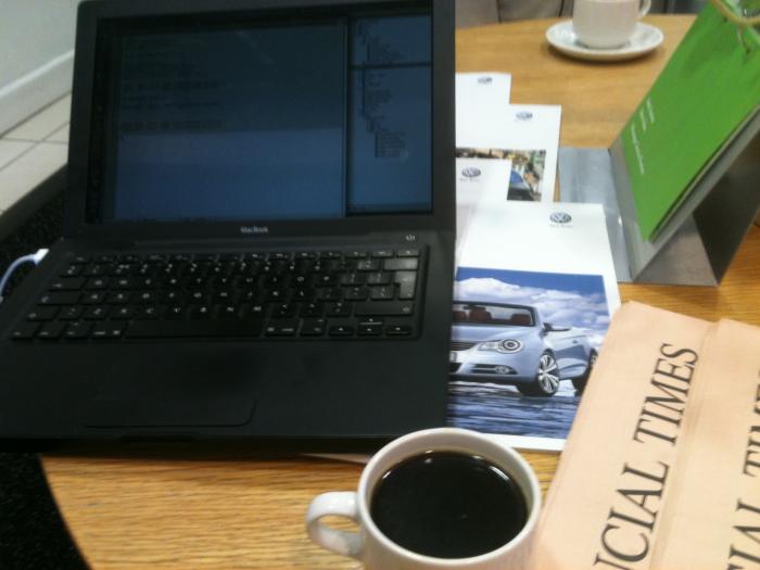 MacBook beside a coffee and VW brochures