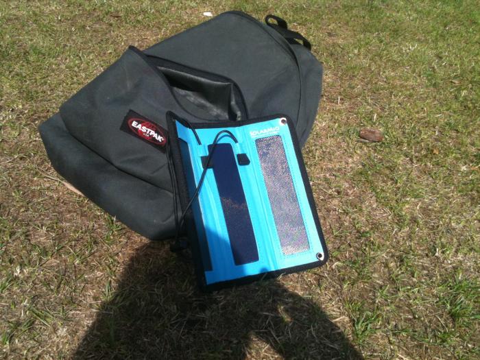 Blue folding solar charger propped against a bag on the grass