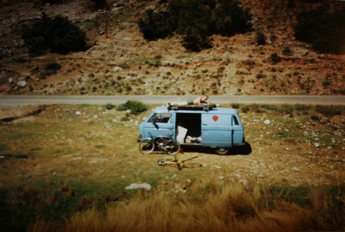 Blue T25 panel van with its side door open in a dry field
