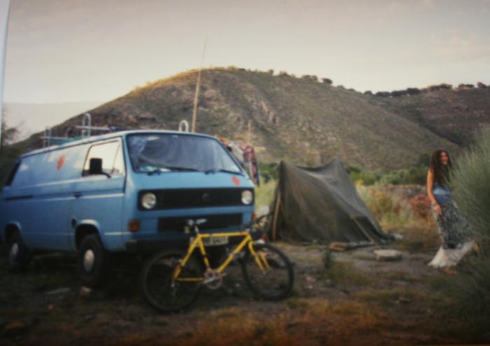 Blue T25 panel van, a bicycle and a tent at a hillside camp