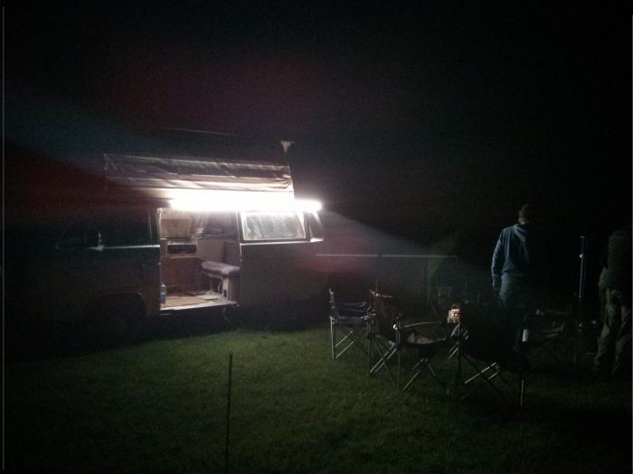 Camp at night lit by a lantern on the van