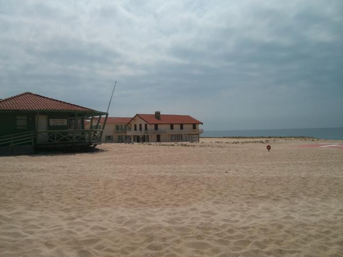Sandy beach with buildings under a cloudy sky
