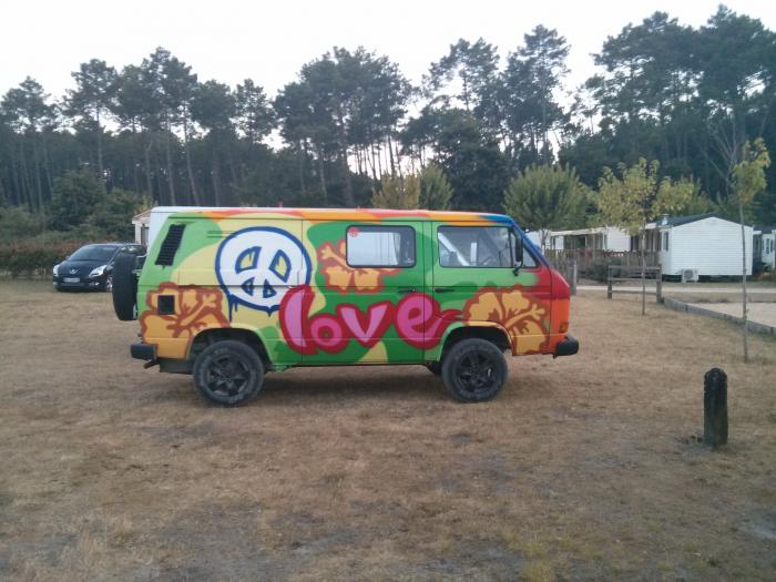 Brightly painted VW T25 with a peace sign and the word love at a campsite